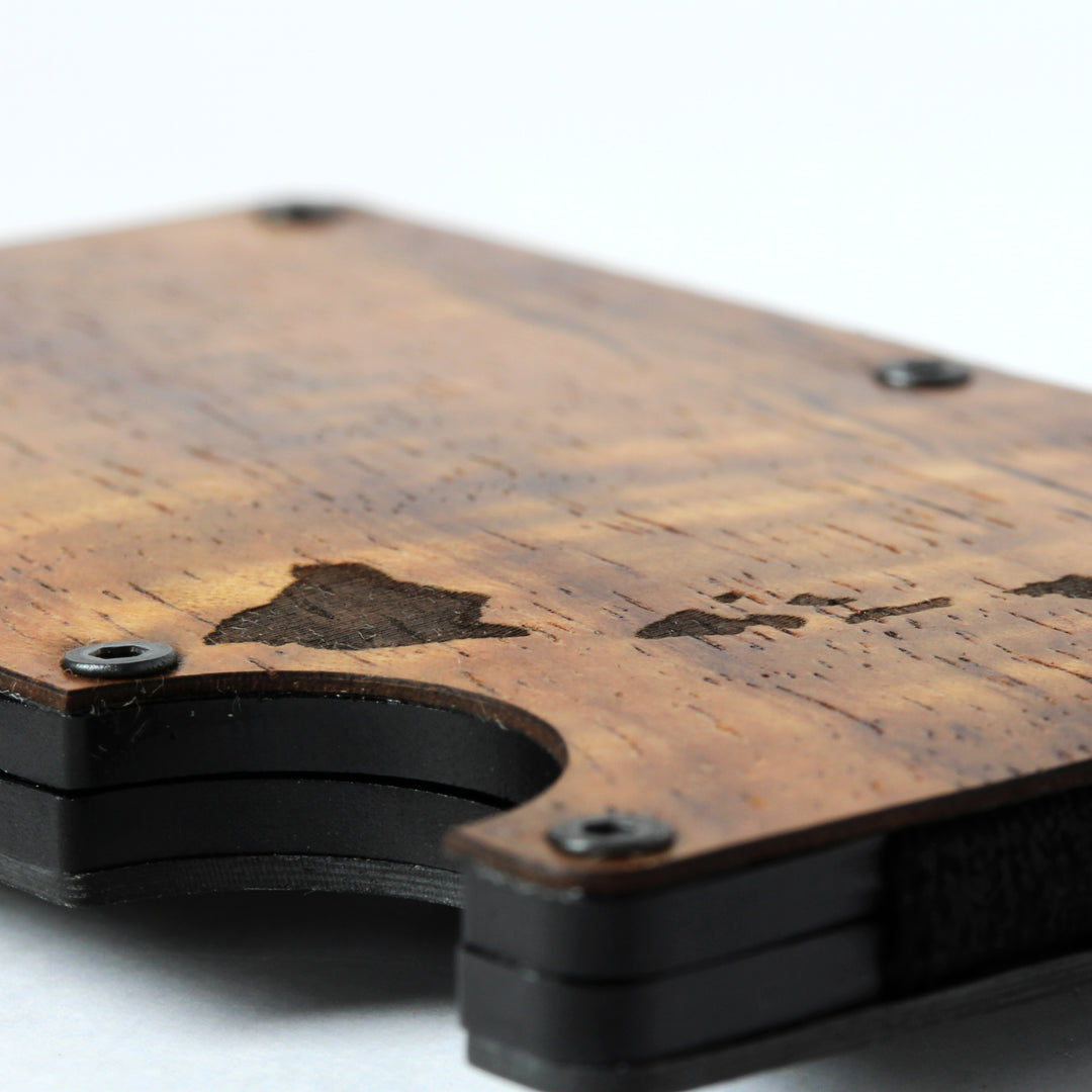 a closeup of a Koa wood minimalist wallet with the laser design of islands in selective focus