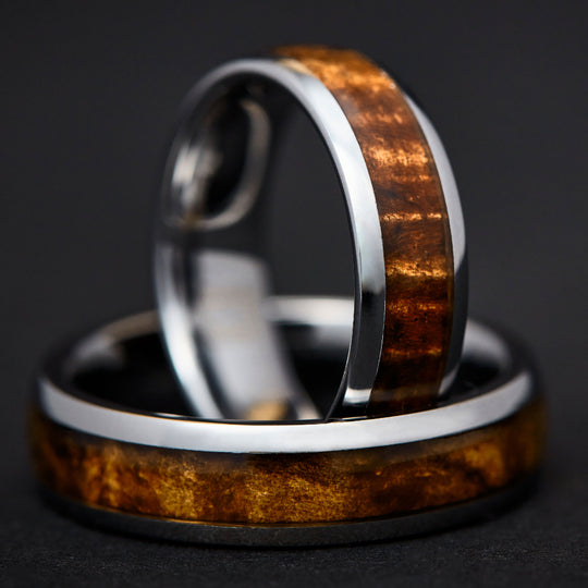 rounded edge koa wood and tungsten rings nestled to prop up one
