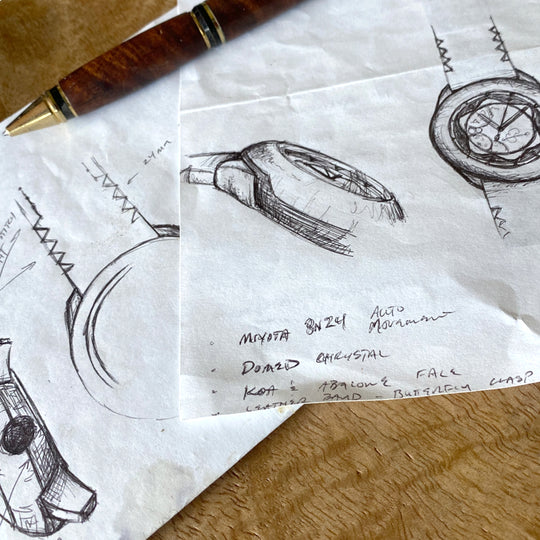 multiple drawings of the Element koa watch design laid out on a mango desk