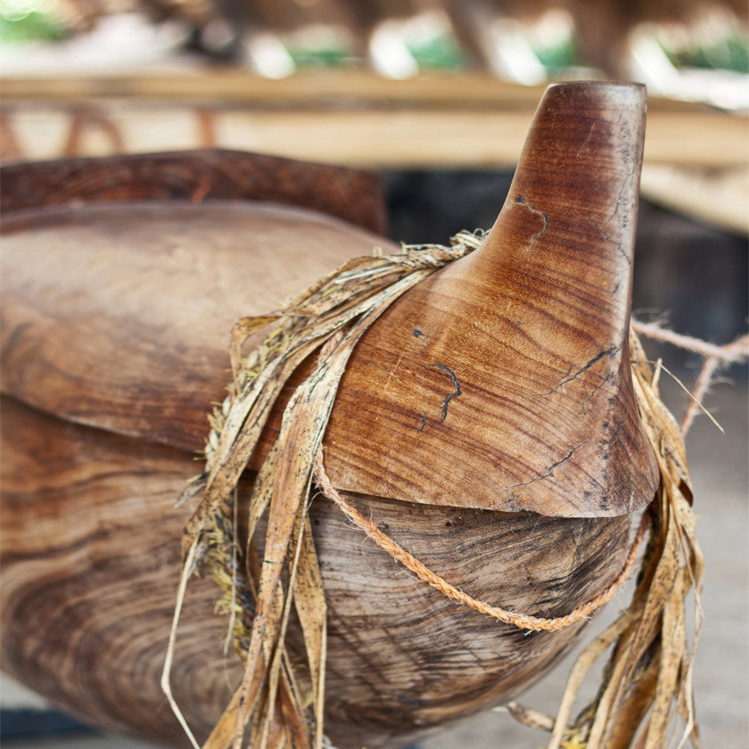 closeup of the front of a Koa Wood outrigger canoe with tea leaf lei wrapped around the front