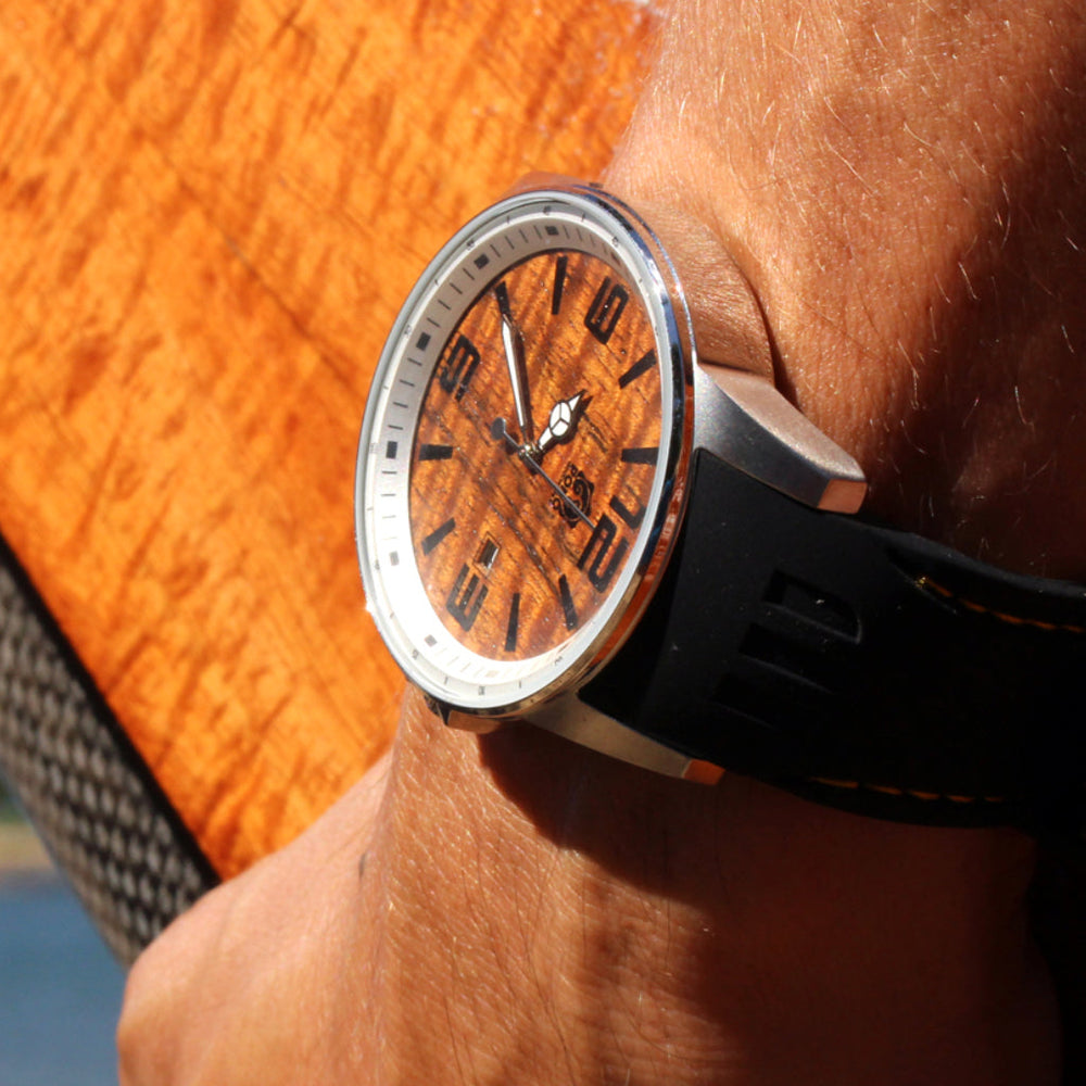 koa wood Surfrider model watch on mans wrist as he holds koa surfboard