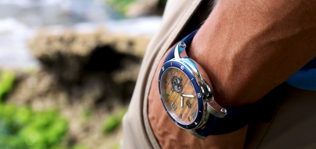 closeup of chrome waterman koa wood watch on wrist with hand in pocket and forest floor in background