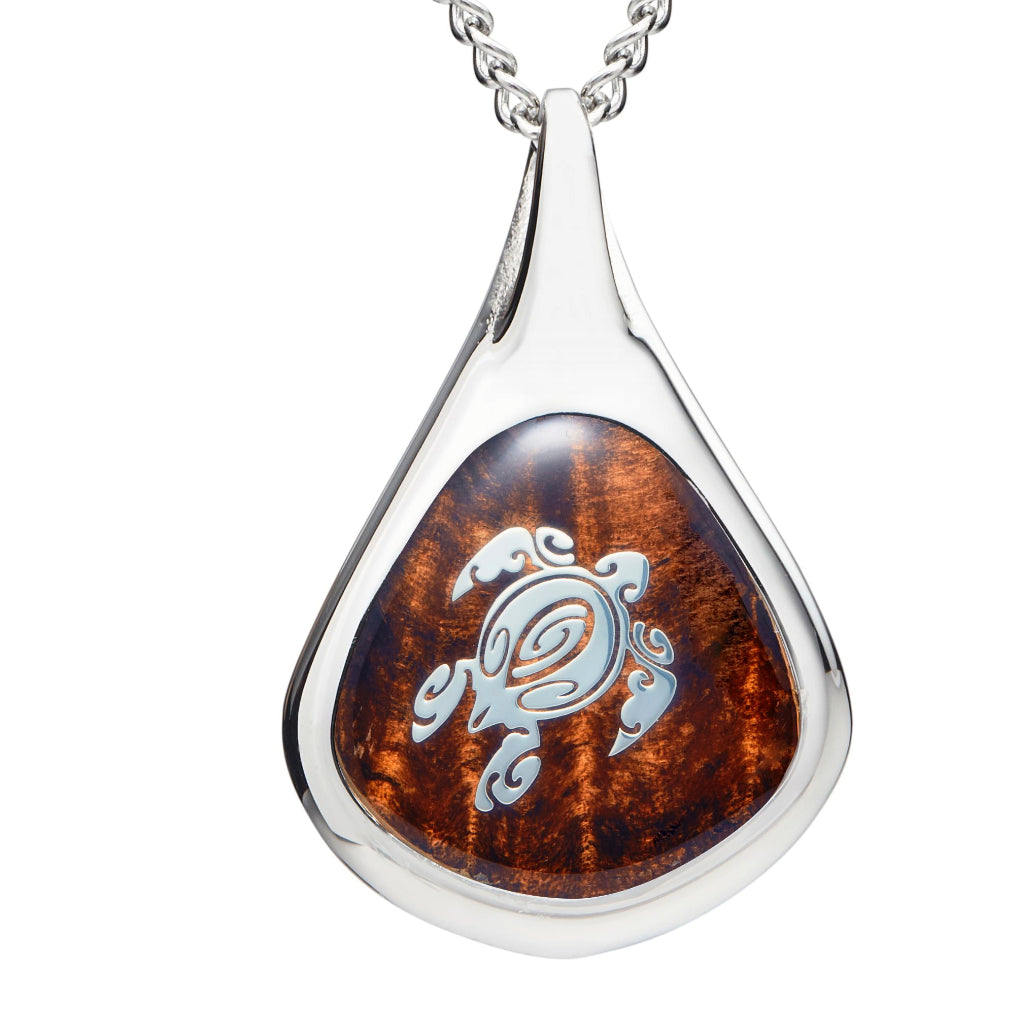 closeup of water drop shaped pendant with koa wood inlay and turtle design overlaid in silver