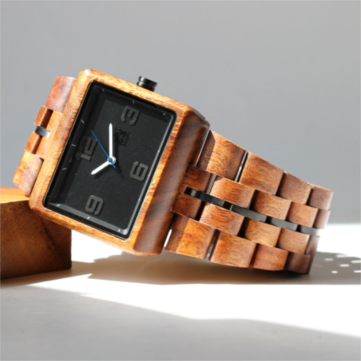 square solid koa wood watch w simple black face leaning against small koa block