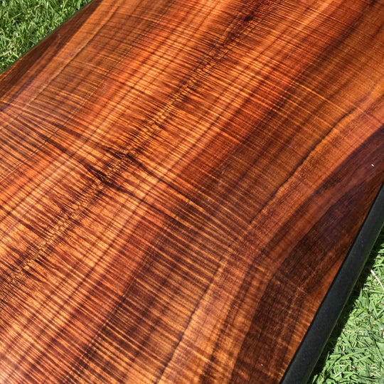 closeup of curly koa wood deck of surfboard