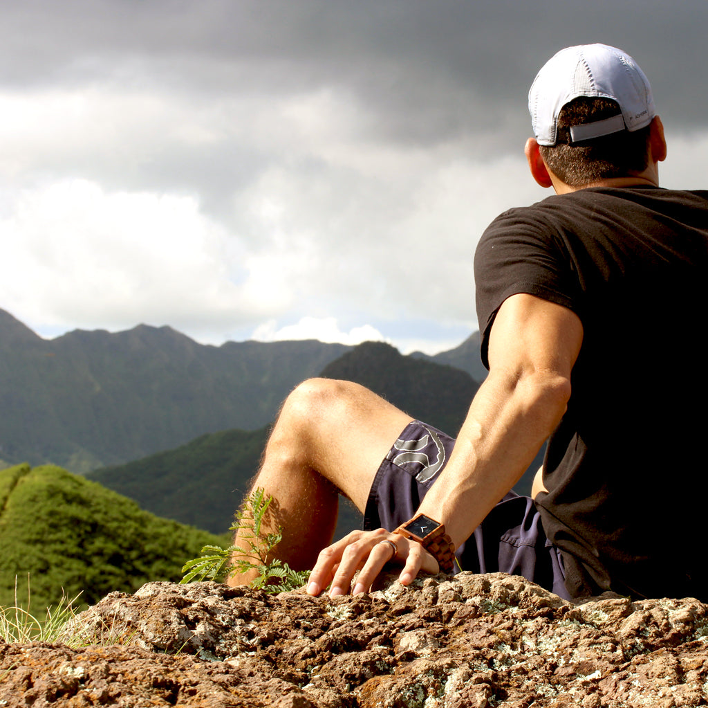 man sitting overlooking mountain wearing square koa wood watch