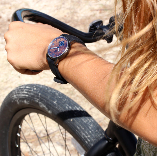 wrist closeup of beautiful women riding beach cruiser bike wearing koa wood and stainless watch